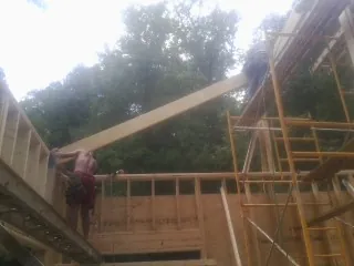 Carpenter raising a rafter beam on a new second story frame in Southbury