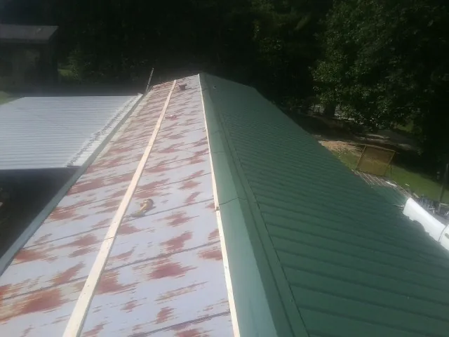 Old rusted panels beside newly installed green metal roofing — Wind Damage Roof Repair by Roofing Brothers in Southbury