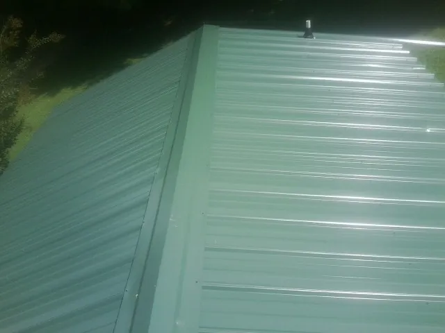 New green metal panels meeting at the ridge of a roof — Flat Roof Repair work by our crew in Southbury