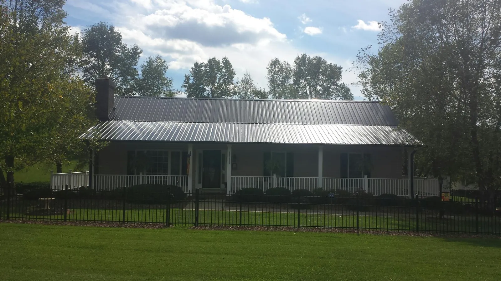 Gray metal roof on a brick ranch with a full width front porch — Gutter Guard Installation work by our crew in Southbury