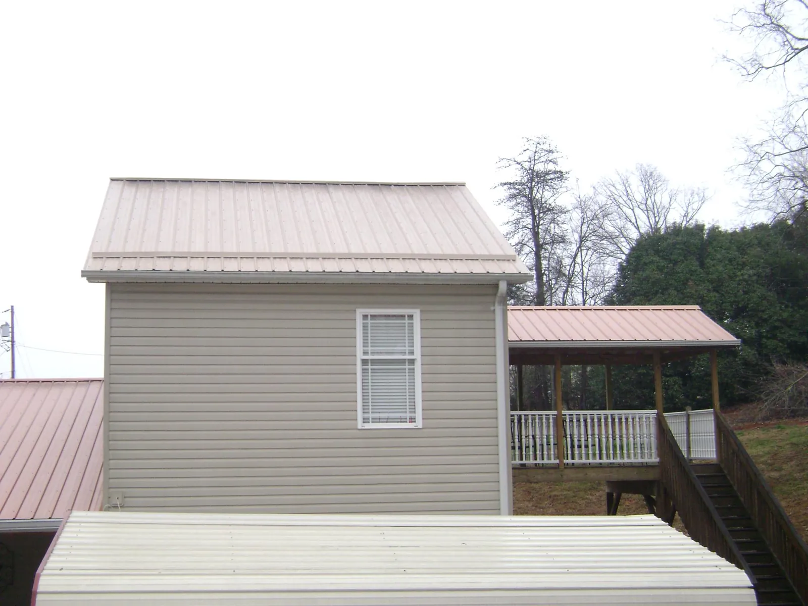 Tan metal roofs on a two story addition and attached porch, from a Roof Replacement job in Southbury
