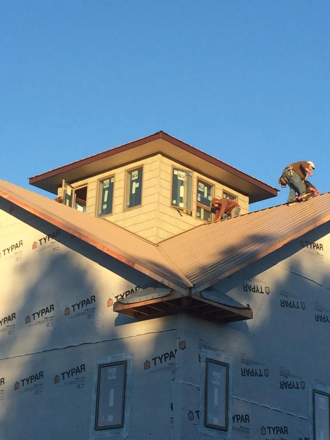 Roofers working around a rooftop cupola on a new metal roof at sunset — Roof Waterproofing in Southbury by Roofing Brothers